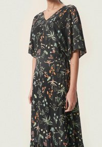 Vestito nero con scollatura a V, maniche corte e vita legata. Presenta un motivo floreale in arancione, verde e blu sullo sfondo nero.