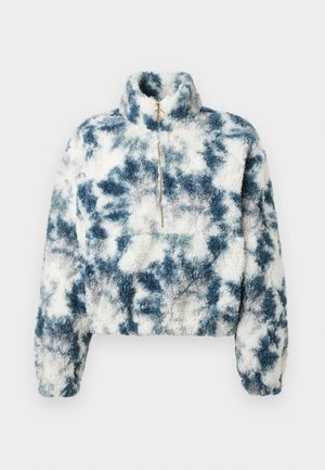 Fleece pullover in blue and white tie-dye pattern with high collar, quarter zip, and cropped design. Soft texture with a boxy fit.
