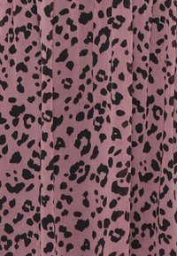 Tissu rose avec des taches léopard noires irrégulières, présentant des plis verticaux dans le matériau.