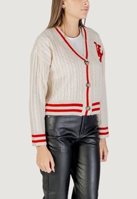 Cardigan in maglia a treccia color avorio con accenti rossi, bottoni doppi e orli a coste. Il design presenta un logo sul petto.