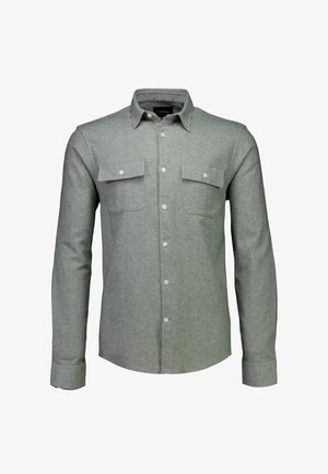 Camisa abotonada de color gris claro, hecha de tela suave, con cuello extendido, mangas largas y dos bolsillos en el pecho con cierres de botón.