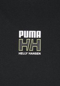 Melns audums ar izteiktu grafisko dizainu. Logo ietver "PUMA" baltā krāsā un "HH" dzeltenā krāsā, ar "HELLY HANSEN" zem tā baltā krāsā.