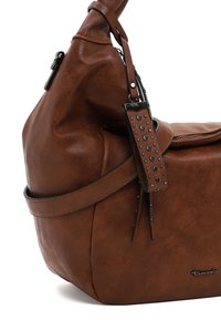 Sac à bandoulière en cuir marron avec sangle décorative cloutée, fermeture éclair latérale et logo de la marque Tamaris en bas à droite.