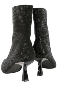 Čierne členkové topánky zdobené brilantmi, s elegantným dizajnom, špicatou špičkou a unikátnym geometrickým opätkom. Logo viditeľné na zadnej strane.