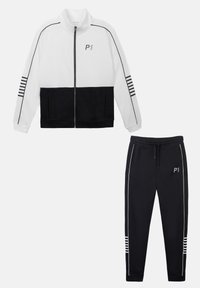 Trainingspak met een witte zip-up jas met zwarte accenten en gestreepte details, gecombineerd met zwarte taps toelopende broek met witte piping.