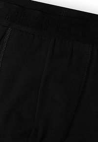 Czarna bielizna o gładkim wykończeniu, z teksturowanym pasem odznaczającym się słowem "SZACUNEK". Widoczne akcenty szwów po bokach.