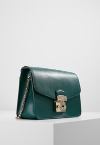 Zelená kožená kabelka s texturovaným povrchem, zlatým kováním na klipu a řetízkem. Klopa se zapínáním na hladký povrch a zaoblenými rohy.