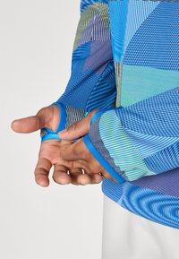 Langarmshirt met een mix van blauwe tinten, geometrische patronen en gestreepte ontwerpen. Het materiaal lijkt rekbaar met contrasterende manchetten.
