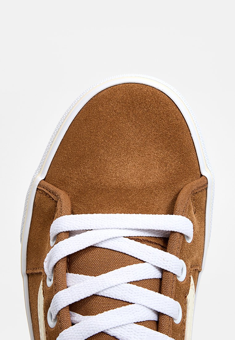 Baskets en daim marron avec lacets blancs, dotées d'un embout arrondi, d'un dessus texturé et d'une semelle blanche contrastante.