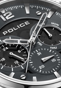 Orologio analogico nero con marcatori e lancette color argento. Presenta più sottodial per giorno, data e un orologio a 24 ore. Cassa in acciaio inossidabile.