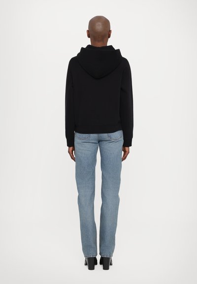 Svart kortermet hettegenser med hette, kombinert med lyseblå rette jeans. Outfiten har et enkelt design uten synlige mønstre eller dekorasjoner.