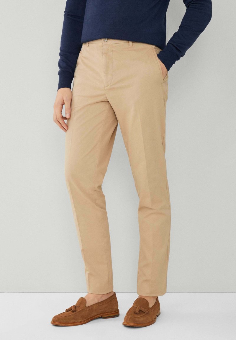 Khaki broek met een getailleerde pasvorm, gemaakt van een zachte stof, met een platte voorkant en zijzakken. Gekoeld met bruine instappers.