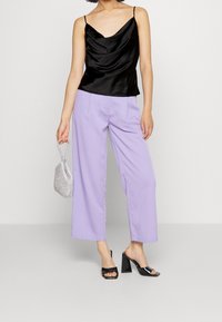 Černý saténový top s krémovým výstřihem doplněný vysokými širokými kalhotami v lila barvě. Doplněno malou stříbrnou kabelkou a černými lodičkami na podpatku.