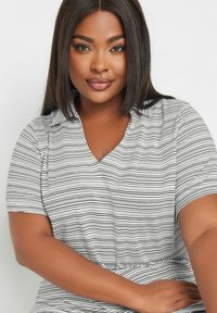 Randig kortärmad topp i vitt och svart, med en v-ringning. Mjuk, lätt tyg med horisontella linjer och avslappnad passform.