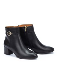 Bottes en cuir noir à hauteur de cheville avec un bout pointu et un talon carré de taille moyenne. Elles présentent une fermeture éclair sur le côté et un accent en métal doré au niveau de la cheville.