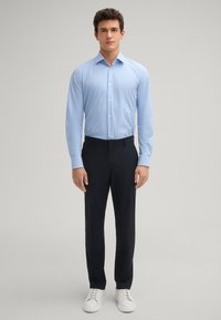 Lichtblauw geblokt overhemd met lange mouwen, gecombineerd met donkerblauwe broek en witte sport sneakers. Eenvoudige, tailored pasvorm.