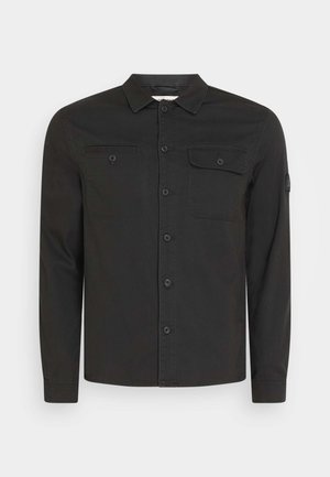 Čierna košeľa na gombíky vyrobená z tkaniny s hladkou textúrou. obsahuje golier, dve náprsné vrecká a dlhé rukávy s gombíkmi na manžetách.