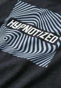 Tessuto grigio scuro con un motivo a linee ondulate blu e nere, con il testo in grassetto che recita "HYPNOTIZED" in bianco al centro.