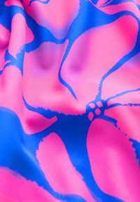 Rozā un zilā ziedu rakstainā auduma ar gludu tekstūru, kurā ir izcelti drosmīgi, abstrakti ziedu motīvi un dinamiskas līnijas.