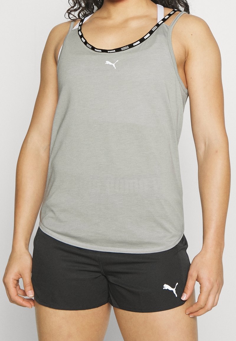 Grå atletisk tanktop med en svart och vit märkeskrage, i kombination med svarta shorts med en liten vit logotyp på sidan.