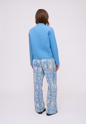Veste matelassée bleu clair avec un col et des manches longues, assortie à un pantalon large bleu à motifs floraux en crème.