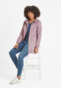 Light purple printed jacket with a hood, elastic cuffs, and zip closure. Worn over a navy shirt with blue jeans and white sneakers.