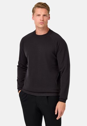 Schwarzer Sweatshirt mit Rundhalsausschnitt, langen Raglanärmeln und gerippten Bündchen. Aus weichem, strukturiertem Stoff gefertigt und mit einem schlichten, minimalistischen Design versehen.