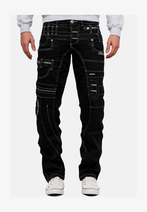 Pantaloni cargo neri con cuciture bianche, multiple tasche, cerniere e design slim fit. Presentano cuciture rinforzate e un accento del logo.