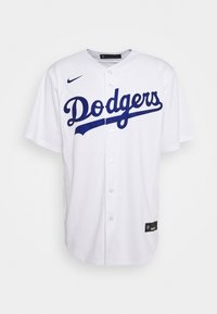 Vit basebolltröja med korta ärmar, blå "Dodgers" text på framsidan, knäppning med knappar och Nike-logga på vänster axel.