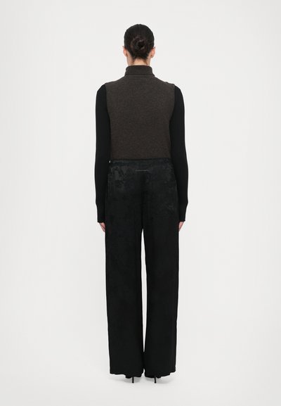Brown, sleeveless turtleneck sweater paired with black, high-waisted, wide-leg pants featuring a subtle floral pattern. Fitted and flowing design.