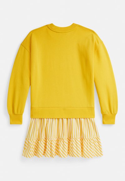 Κίτρινο φούτερ με μακριά μανίκια συνοδευόμενο από φούστα με βολάν και ρίγες σε λευκό και ανοιχτό κίτρινο. Διαθέτει ελαστικά μανσέτα και στρογγυλή λαιμόκοψη.