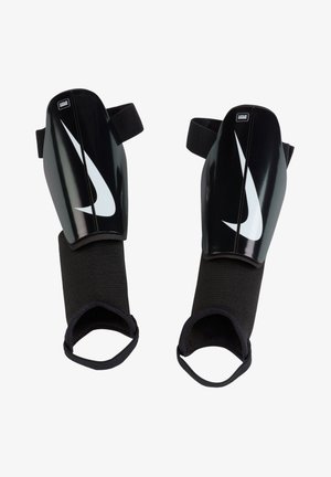 Black plastic shin guards with a large white Nike swoosh. Features adjustable black straps and a padded black textile lining for comfort.