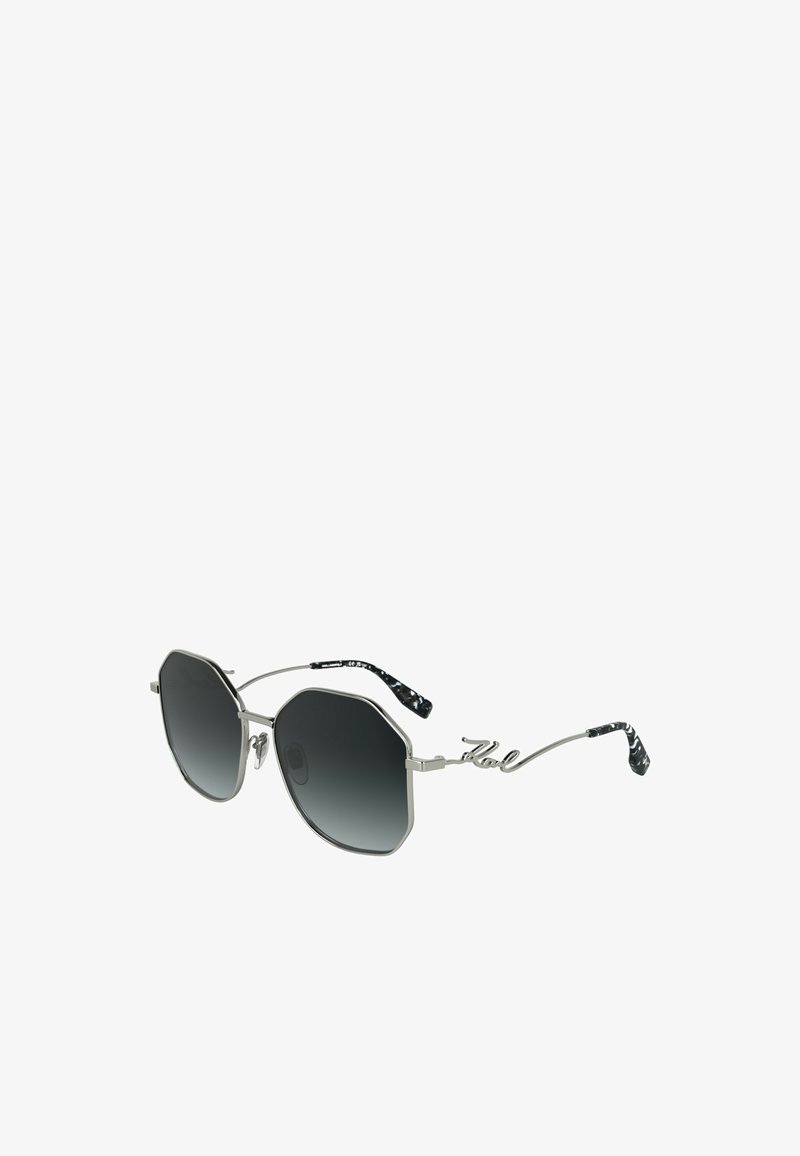 Occhiali da sole ottagonali con lenti nere sfumate, montatura in metallo argento e braccia in filo uniche con una texture a motivo bianco e nero.