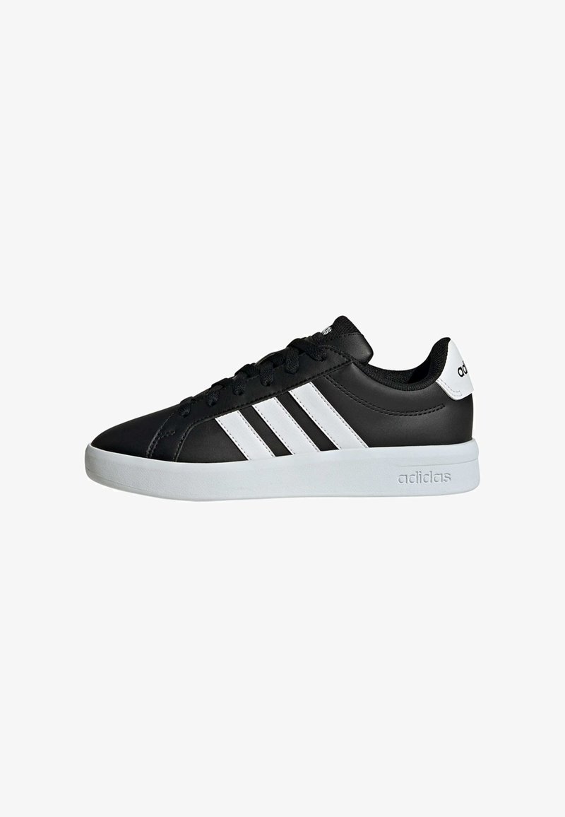 Baskets basses noires Adidas avec des bandes blanches, une semelle blanche et des lacets noirs, vues de côté sur un fond blanc.