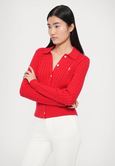 Rdeč pulover s pletenim vzorcem, z ovratnikom, zapenjanjem na gumbe ter rebrastimi manšetami in robom, prikazan na nevtralni podlagi.