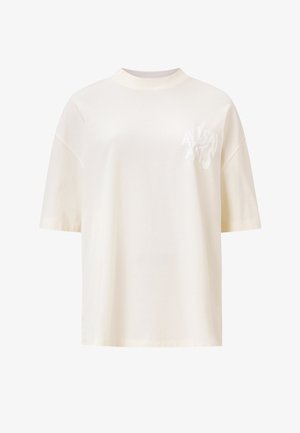 Cremefarvet t-shirt med korte ærmer lavet af bomuld. Har en afslappet pasform, rund halsudskæring og et subtilt logo i samme tone foran. Glat tekstur.