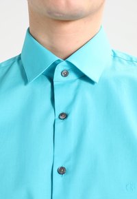 Tegenwoordig turquoise overhemd met een spread collar en drie donkere knopen. Gladde stof met een subtiele glans, CK-logo op de onderkant rechts.