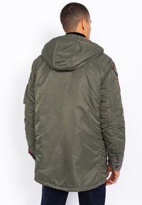 Oliwkowa parka z kapturem, cechująca się pikowanym wzorem, elastycznymi mankietami oraz naszywką na lewym ramieniu. Widok z tyłu ukazujący bezszwowy design.