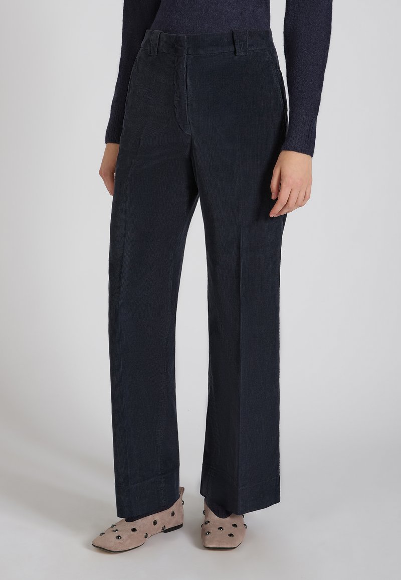 Navy corduroy broeken met een rechte snit, beschikken over een textuur en zijzakken, gecombineerd met lichtgekleurde schoenen versierd met zwarte stippen.