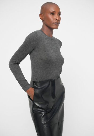 Siva dolgi rokav prilegajoča majica iz mehkega blaga v kombinaciji z visokim črnim usnjeni svinčnik krilom, ki ima stranske žepe in gladko teksturo.