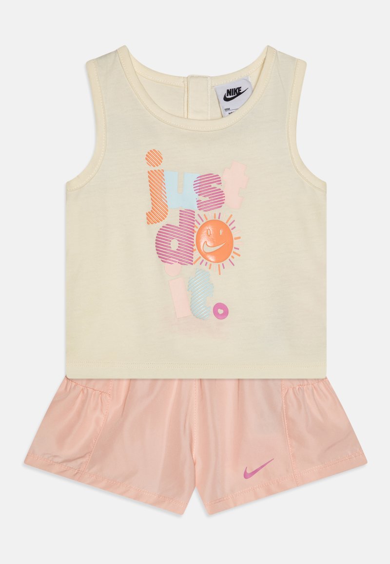 Top amarelo-claro sem mangas com uma estampa "simplesmente faça", combinado com calções rosa-claro suaves que apresentam um logo da Nike na bainha.