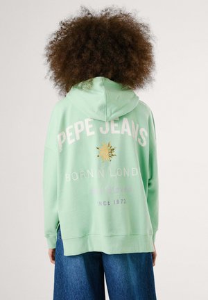Felpa verde menta con tasca frontale, grande design testuale posteriore in bianco e oro, tessuto morbido e vestibilità oversize con polsini a costine.