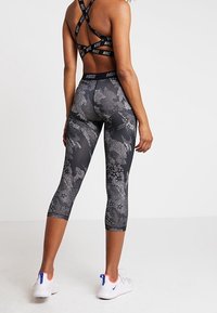 Czarno-szare legginsy w wzory z wysokim stanem, wykonane z elastycznego materiału, o długości capri i gładkiej, jedwabistej fakturze.