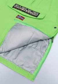 Giacca verde con un esterno liscio e un interno imbottito di colore argento. Presenta una tasca con zip e una patch che mostra la bandiera della Norvegia.