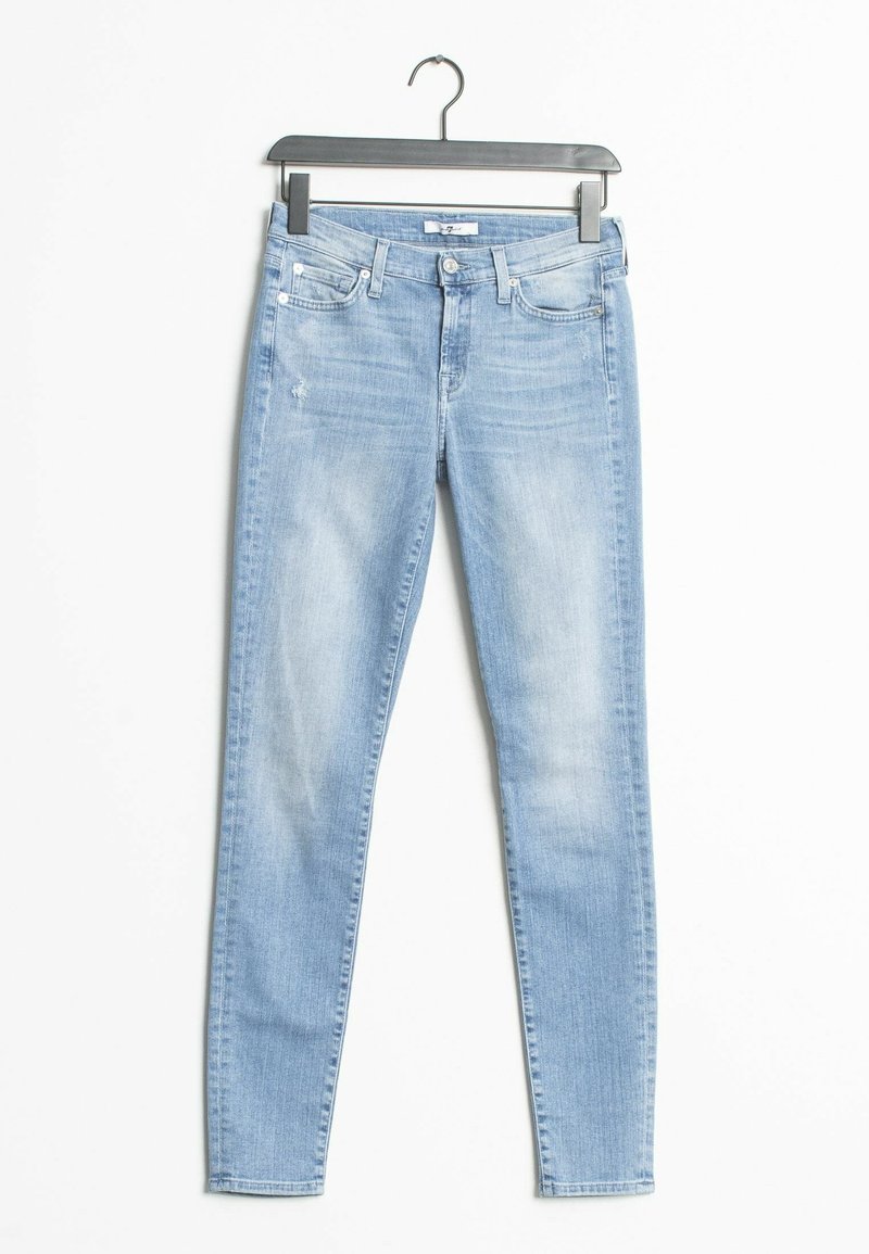 Jeans ajustados de color azul claro con una textura desgastada, diseño básico de cinco bolsillos, sutiles arrugas y cierre de botón. Colgados de una percha de metal negro.