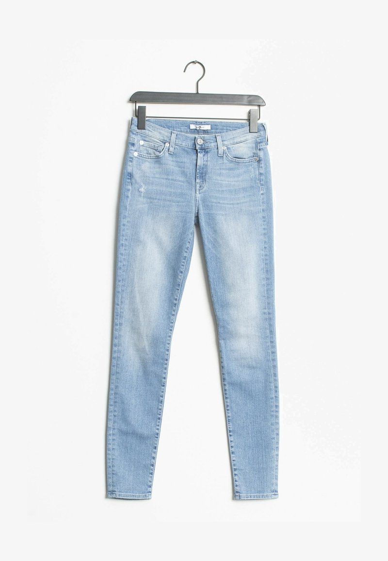 Jean skinny bleu clair avec une texture délavée, design basique à cinq poches, un léger effet de décoloration, et une fermeture à bouton. Suspendu à un cintre en métal noir.