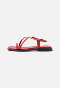 Røde flate sandaler med tynne stropper, spenne lukking og svart gummisåle. Glatt tekstur og minimalistisk design, inkludert en formet fotseng.