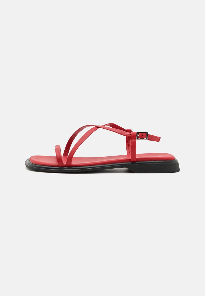 Røde flate sandaler med tynne stropper, spenne lukking og svart gummisåle. Glatt tekstur og minimalistisk design, inkludert en formet fotseng.