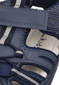 Sandalia para niños en azul y gris con parte superior sintética, paneles de malla, correa ajustable y franjas blancas contrastantes en los lados.