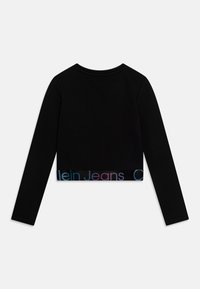 Musta pitkähihainen lyhyt paita, jossa pyöreä pääntie ja merkkilogo, jossa on monivärinen teksti "Calvin Klein Jeans." Sileä, joustava kangas.